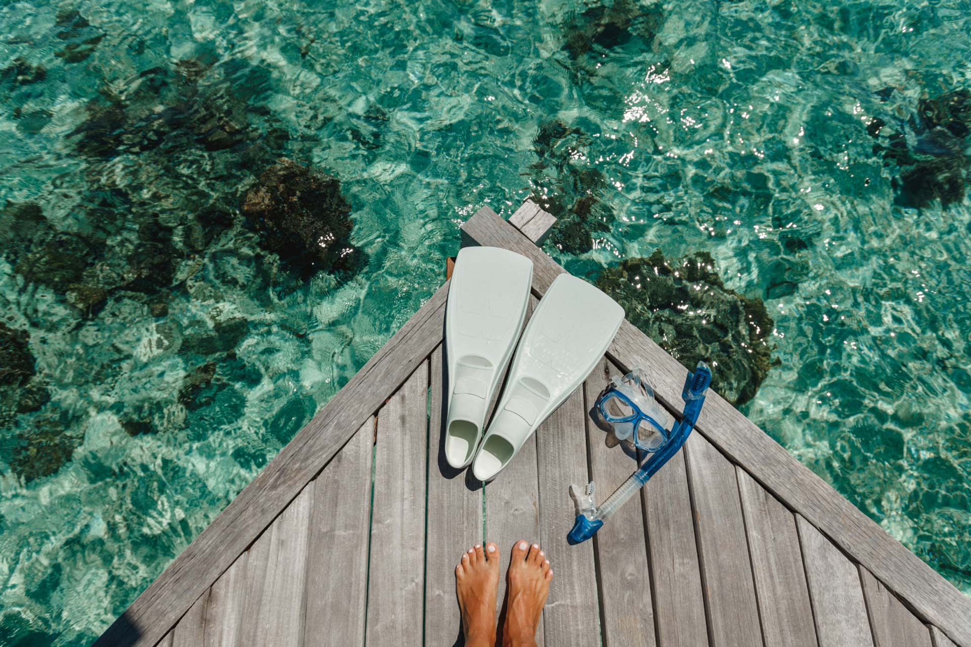 Aerial of feet and snorkeling equipment on the dock